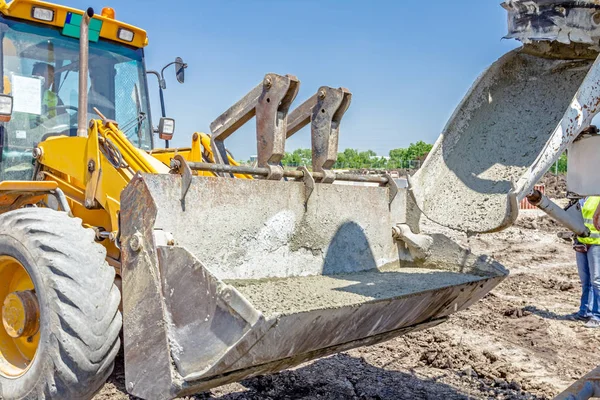 Mélangeur de camion en cours de coulée de béton dans la pelle bulldozer . — Photo