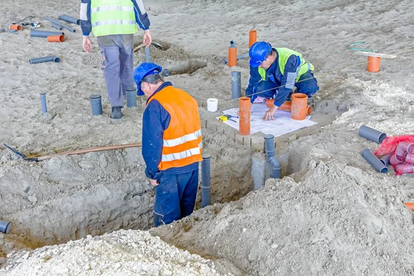 Team von Riggern justiert und montiert Sanitärrohre auf Baustelle. — Stockfoto