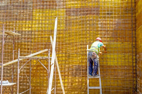 Trabajador está atando barras de refuerzo para hacer una nueva rejilla de refuerzo en el molde de madera . — Foto de Stock