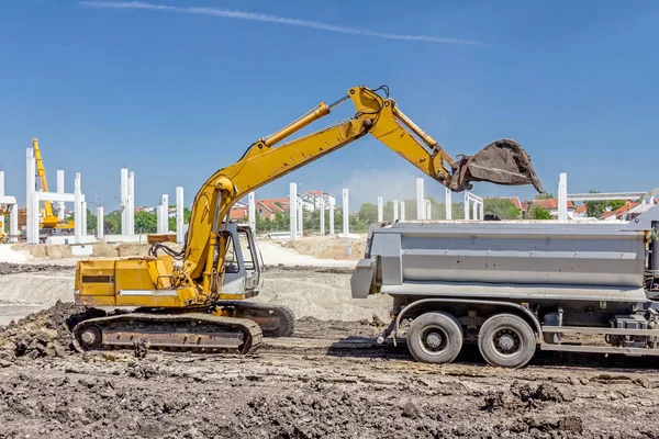 Excavadora está cargando un camión en el sitio de construcción — Foto de Stock