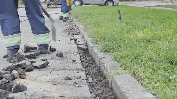 Arbetstagare med en spade samlar bruten asfalt bakom jackhammer — Stockvideo