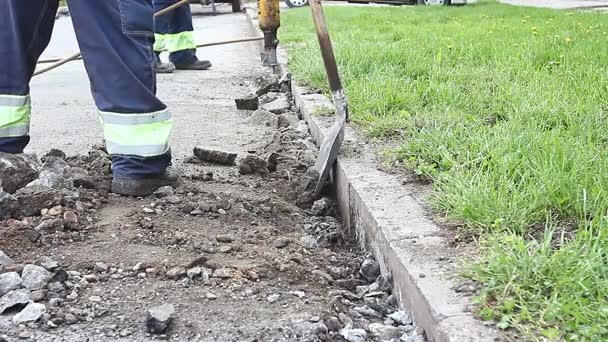 Trabalhador com uma pá recolhe asfalto quebrado — Vídeo de Stock