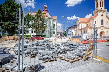 Kaldırım döşeme ahşap palet üzerinde yığılmış yığını malzemeleri ile çitlerle çevrili.