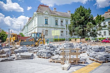Kaldırım döşeme ahşap palet üzerinde yığılmış yığını malzemeleri ile çitlerle çevrili.