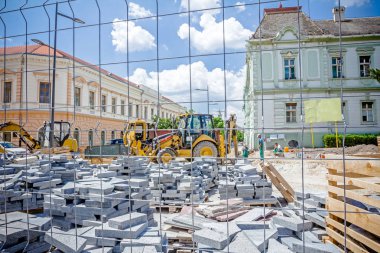 Kaldırım döşeme ahşap palet üzerinde yığılmış yığını malzemeleri ile çitlerle çevrili.