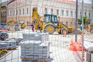 Kaldırım döşeme ahşap palet üzerinde yığılmış yığını malzemeleri ile çitlerle çevrili.