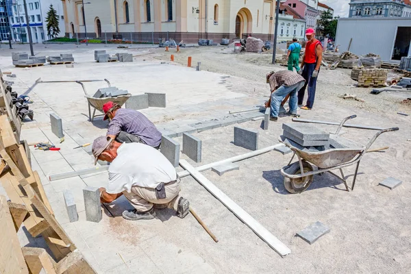 Los albañiles se ajustan a la losa, el trabajo en equipo — Foto de Stock