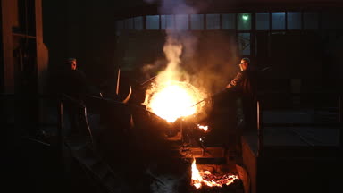 İşçiler uzun çubuklar ile yüksek fırın atölye erimiş metal pislik kaldırdığınızı