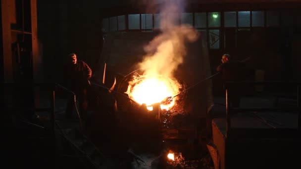 Arbeiter mit langen Stangen entfernen Schmutz aus geschmolzenem Metall in der Hochofenwerkstatt — Stockvideo