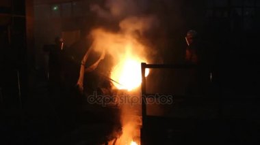 İşçiler uzun çubuklar ile yüksek fırın atölye erimiş metal pislik kaldırdığınızı