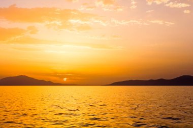 deniz üzerinde bulutlu gün batımı