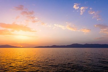 deniz üzerinde bulutlu gün batımı