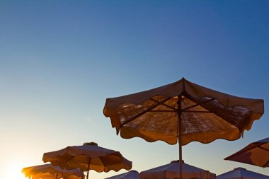 Şemsiye şezlong ile güneşle Halk Plajı görünümünü siluet