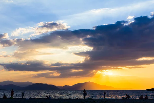 Silhouette eines Sonnenuntergangs mit Menschen am Strand — Stockfoto