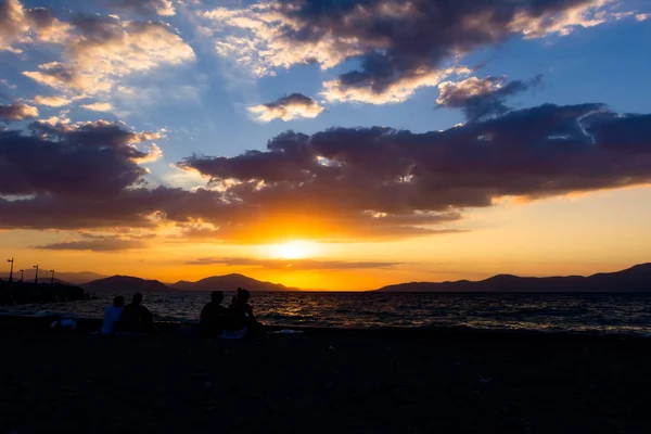 Foto silueta de puesta de sol con gente junto a la playa — Foto de Stock