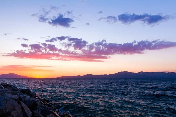 Purple rocks on coastline cloudy sunset over sea — Stock Photo, Image