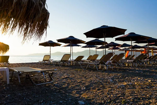 Silhouette view of thatched umbrellas with loungers — Stock Photo, Image