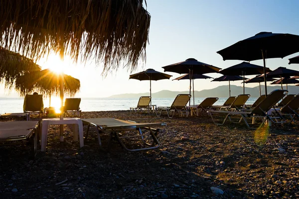 Pohled na siluetu doškovými slunečníky s lehátky pláži — Stock fotografie