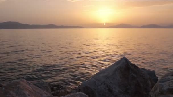 Rochas roxas na costa pôr do sol nublado sobre o mar — Vídeo de Stock