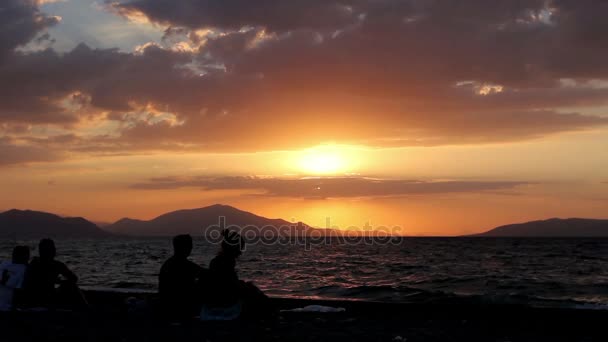 Siluett bild på solnedgången med folk på stranden — Stockvideo