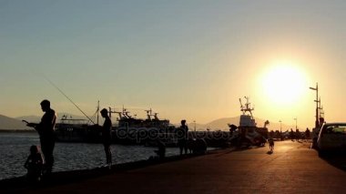 Gün batımında iskelede Balık tutma bir insan kontrast atış