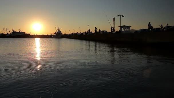 Silhouetted shot of a people fishing on pier at sunset — Stock Video