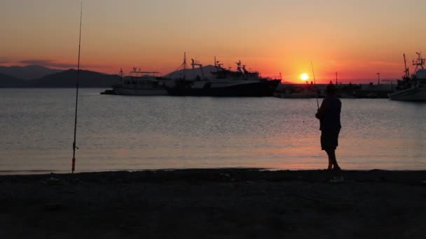 Силуетний постріл літнього чоловіка риболовля на причалі на заході сонця — стокове відео