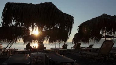 Thatched şemsiye şezlong yanındaki sahil şeridi ile görünümünü siluet 