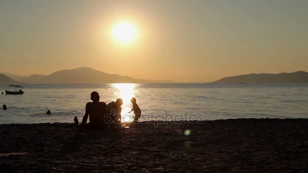 Siluett bild på solnedgången med folk på stranden — Stockvideo