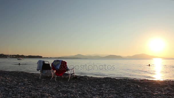 Dois lugares sentados ao lado das espreguiçadeiras ao lado da costa, praia — Vídeo de Stock