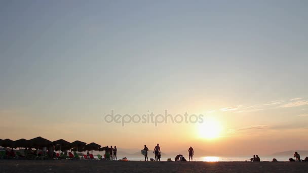 Silhouetted βολή του ηλιοβασιλέματος με ανθρώπους στην παραλία — Αρχείο Βίντεο