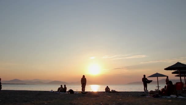 Scatto silhouetted del tramonto con la gente dalla spiaggia — Video Stock