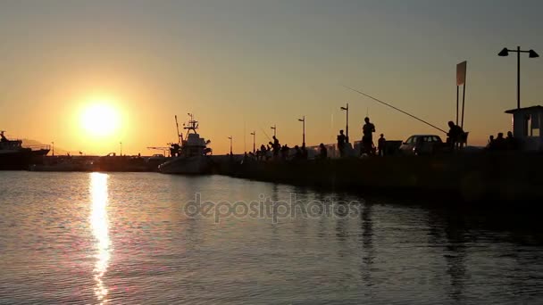 Silhouetted shot of a people fishing on pier at sunset — Stock Video