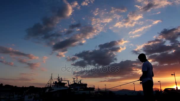 해질녘 부두에서 낚시 하는 소년의 silhouetted 샷 — 비디오