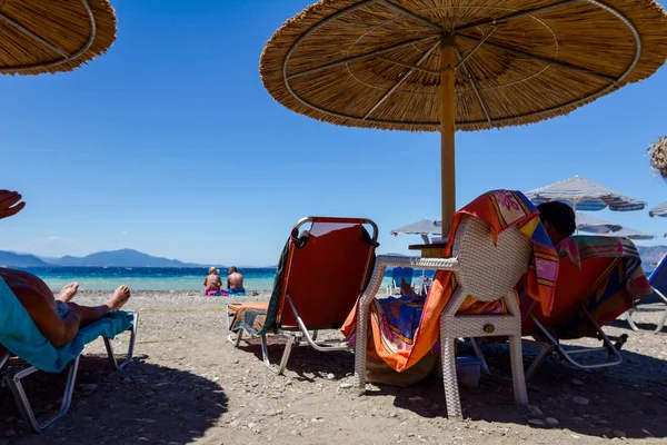 Ludzi na plaży pod parasole wykonane ze słomy i leżaki — Zdjęcie stockowe