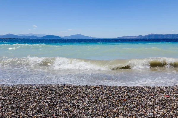 Deniz köpüklü dalgalar kırılıyor bir plajda çakıl karşı sahil