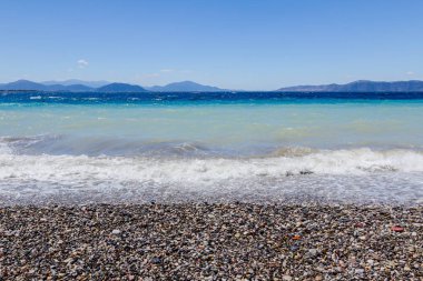 Deniz köpüklü dalgalar kırılıyor bir plajda çakıl karşı sahil