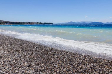 Deniz köpüklü dalgalar kırılıyor bir plajda çakıl karşı sahil