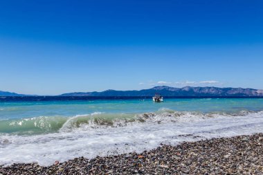 Küçük iskele tekne köpüklü dalgalar ile plajına yakın bağlantılı