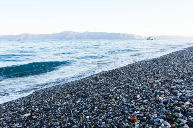 Sunrise, sabah deniz çakıl üzerinde karşı köpüklü dalgalar ile bir 