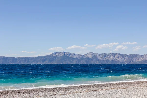 Deniz köpüklü dalgalar kırılıyor bir plajda çakıl karşı sahil