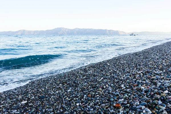 Sunrise, sabah deniz çakıl üzerinde karşı köpüklü dalgalar ile bir 