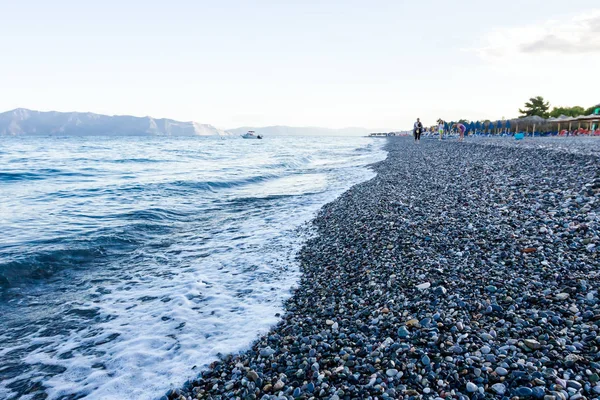 Sunrise, sabah deniz çakıl üzerinde karşı köpüklü dalgalar ile bir 