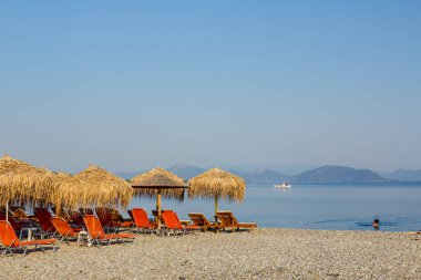 Kıyı şeridi yanındaki plastik şezlong ile thatched şemsiye 