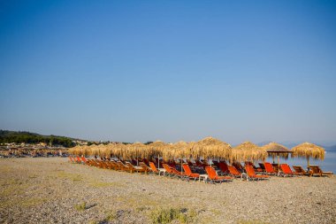 Kıyı şeridi yanındaki plastik şezlong ile thatched şemsiye 