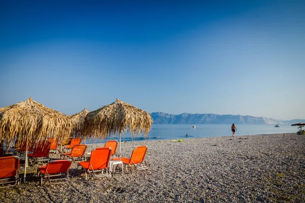 Kıyı şeridi yanındaki plastik şezlong ile thatched şemsiye 