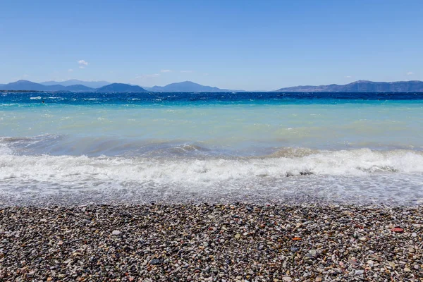 Deniz köpüklü dalgalar kırılıyor bir plajda çakıl karşı sahil