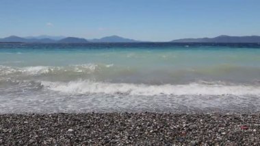 Deniz köpüklü dalgalar kırılıyor bir plajda çakıl karşı sahil
