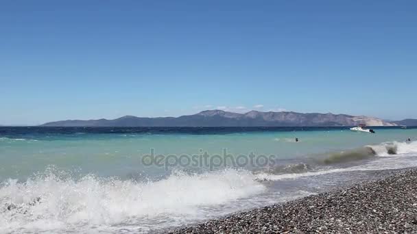 La mer brise les vagues mousseuses contre les cailloux sur la plage, la côte — Video
