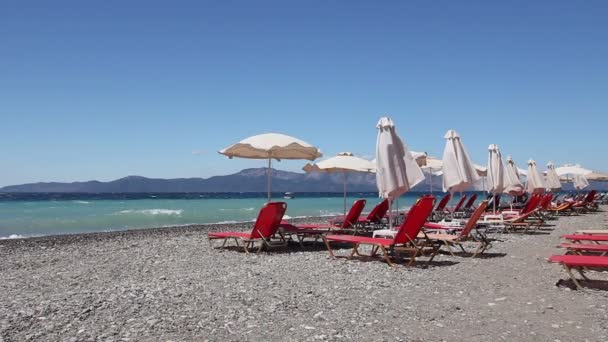 Paraplu's met ligstoelen geplaatst naast de kustlijn — Stockvideo